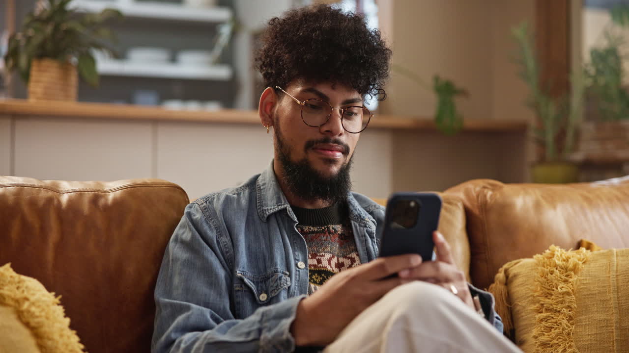 Smiling man using his phone on the couch