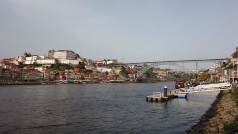 aerial drone view of ribeira district with colorful buildings lining douro river and dom luis i bridge in porto, portugal, capturing riverside charm and iconic cityscape under clear daylight