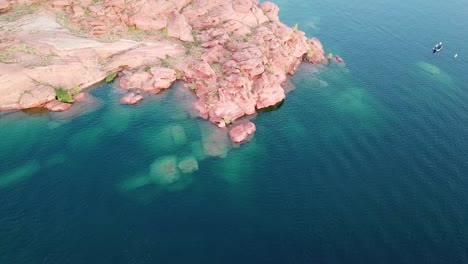 red rocky island coast, blue water reservoir and boat in sand hollow state park, utah usa, drone aerial view