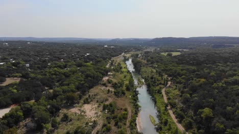 Volando-Sobre-El-Río-Que-Muestra-Una-Gran-Sección-Del-Río,-La-Región-Montañosa-Y-Las-Colinas-En-El-Fondo---Imágenes-Aéreas-Del-Río-Blanco-En-Wimberly,-Tx