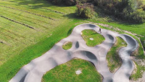 Vista-Aérea-De-Pájaros-De-Una-Persona-Que-Monta-Una-Bicicleta-En-Un-Circuito-De-Bicicletas-En-Un-Parque