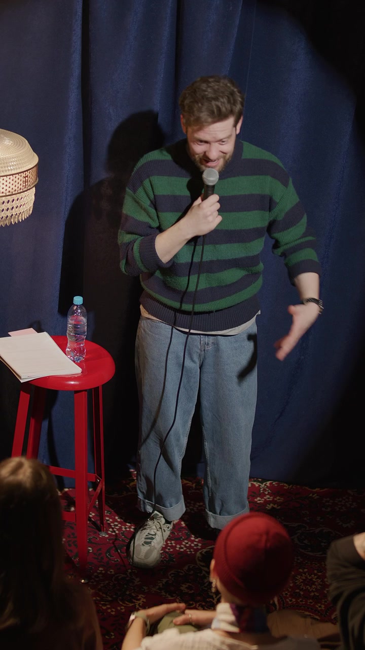 Joyful Male Comedian Performing Stand Up with Microphone on Stage