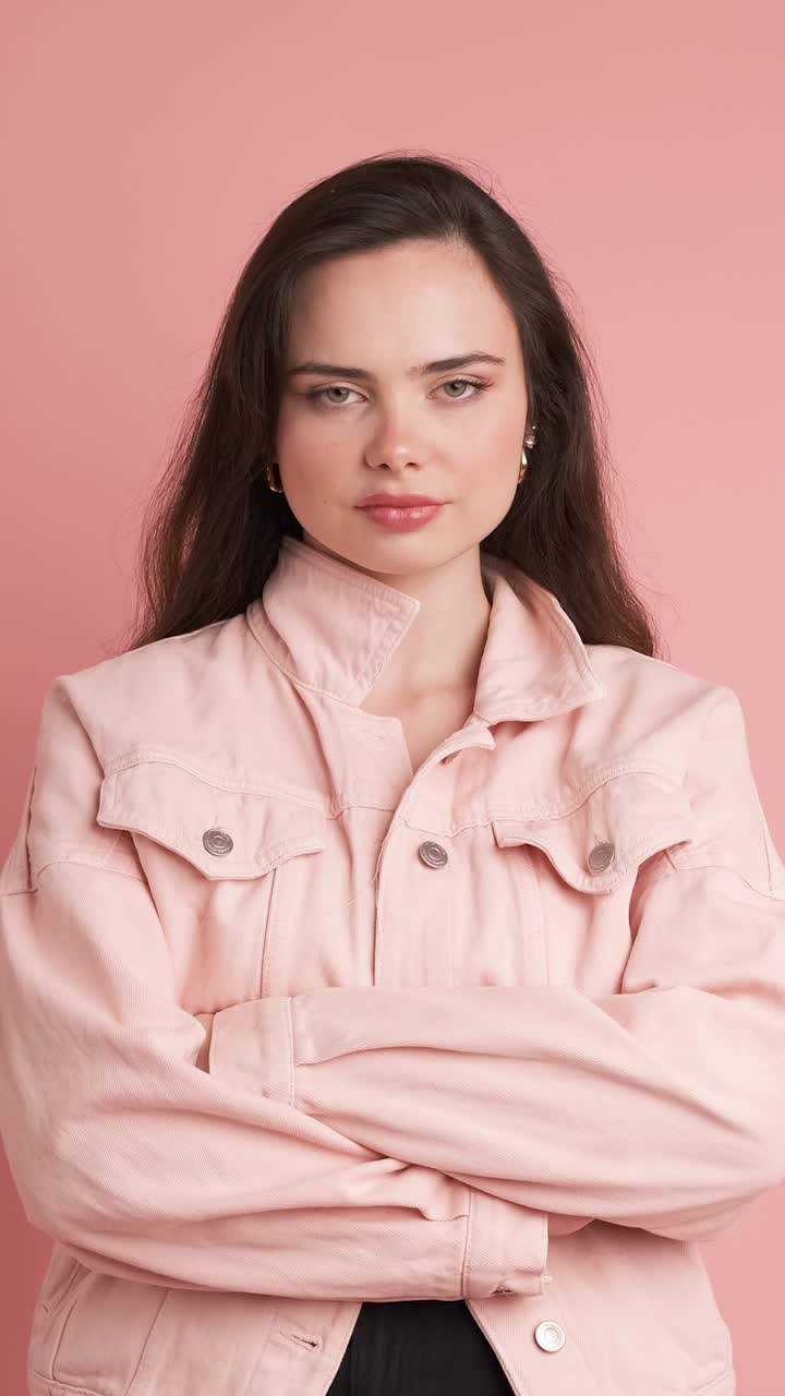 Serious young woman thinking in pink studio