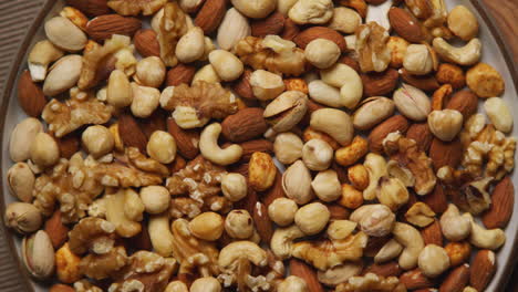 close up overhead shot of bowl containing cashews dry roasted peanuts pistachio walnuts and hazelnut nuts revolving 1