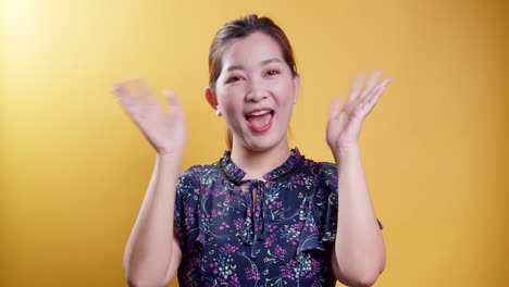친절하고 친근한 아시아 여성이 매력적인 환영이나 작별인사로 손을 흔들며 웃는다