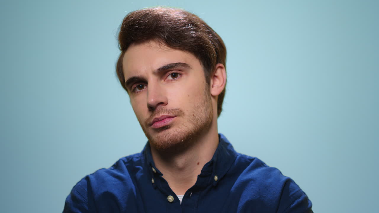 Disappointed man looking at camera in studio. Guy with unhappy face expression
