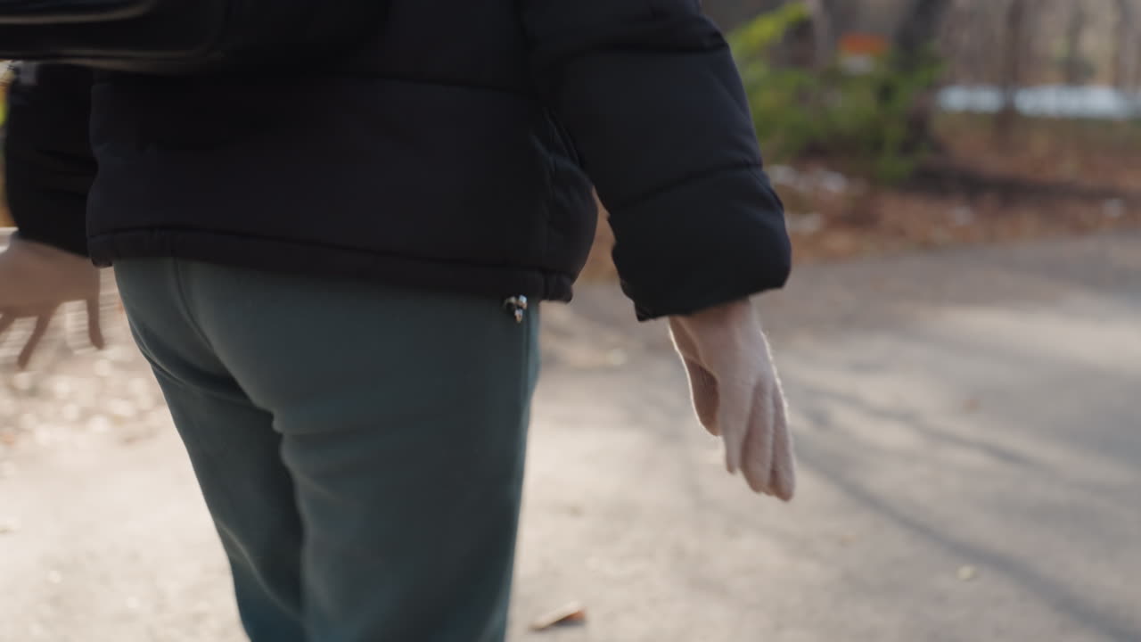 Mano che si porta verso la tasca mentre si cammina. Movimento furtivo all'altezza dell'anca, dettagli di cerniera e tessuto. Implicito tentativo di furto o borseggio, atmosfera tesa e passanti sfocati sullo sfondo.