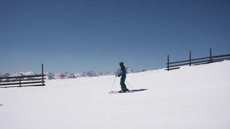 Skier-going-down-the-slope-making-turns-with-the-mountain-panorama-in-the-background
