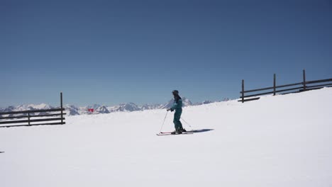 skier going down the slope making turns with the mountain panorama in the background