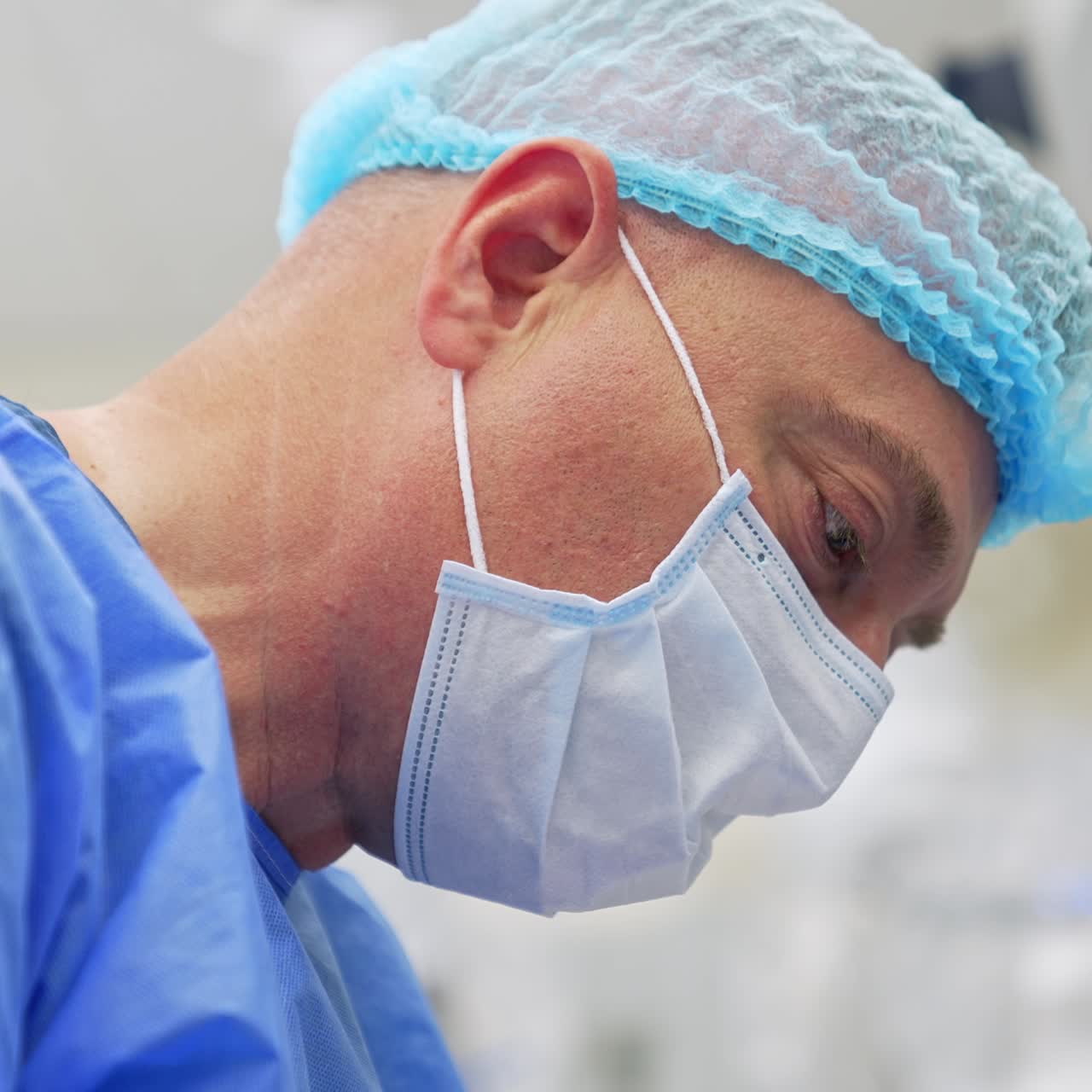 Adult male doctor in mask and cap busy with operation. Portrait of a confident medical professional doing his work. Close up