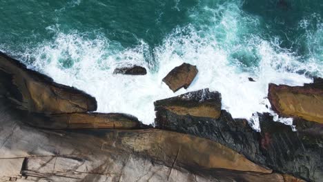 drone shot from above of sea water crashing on cliff rocks