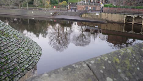 gimbal parallax of perfectly still river from a bridge in historic city with reflective water and birds gliding