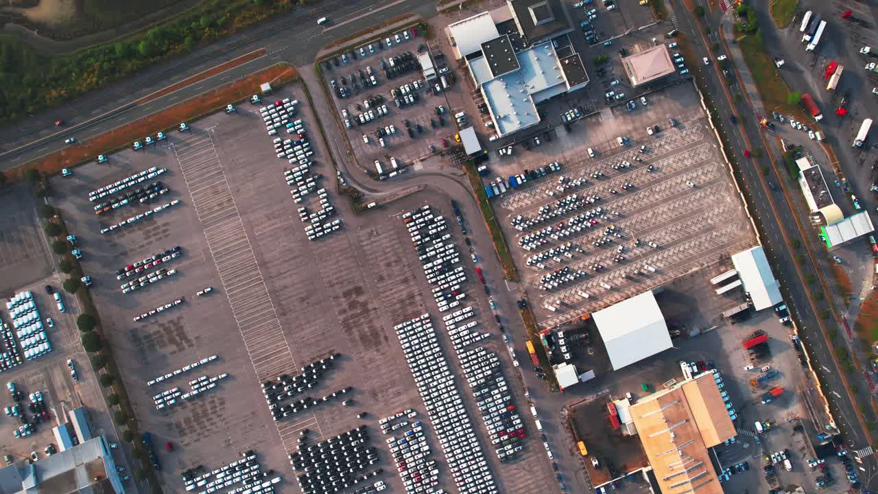 almacén industrial con coches en el estacionamiento, tiro de drones giratorios de arriba hacia abajo