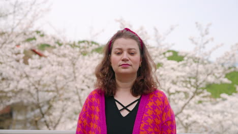 viajero femenino mirando a la cámara con flores de cerezo en el fondo