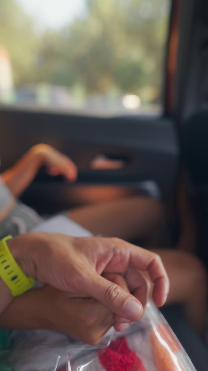 Close-up of hands with a yellow wristband inside a car