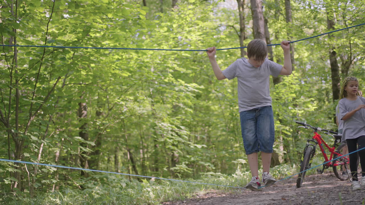 Small boy in climbing equipment in a rope Park. Group of Caucasian children training at boot camp. In the children camp children are taught to overcome obstacles with the help of a rope crossing