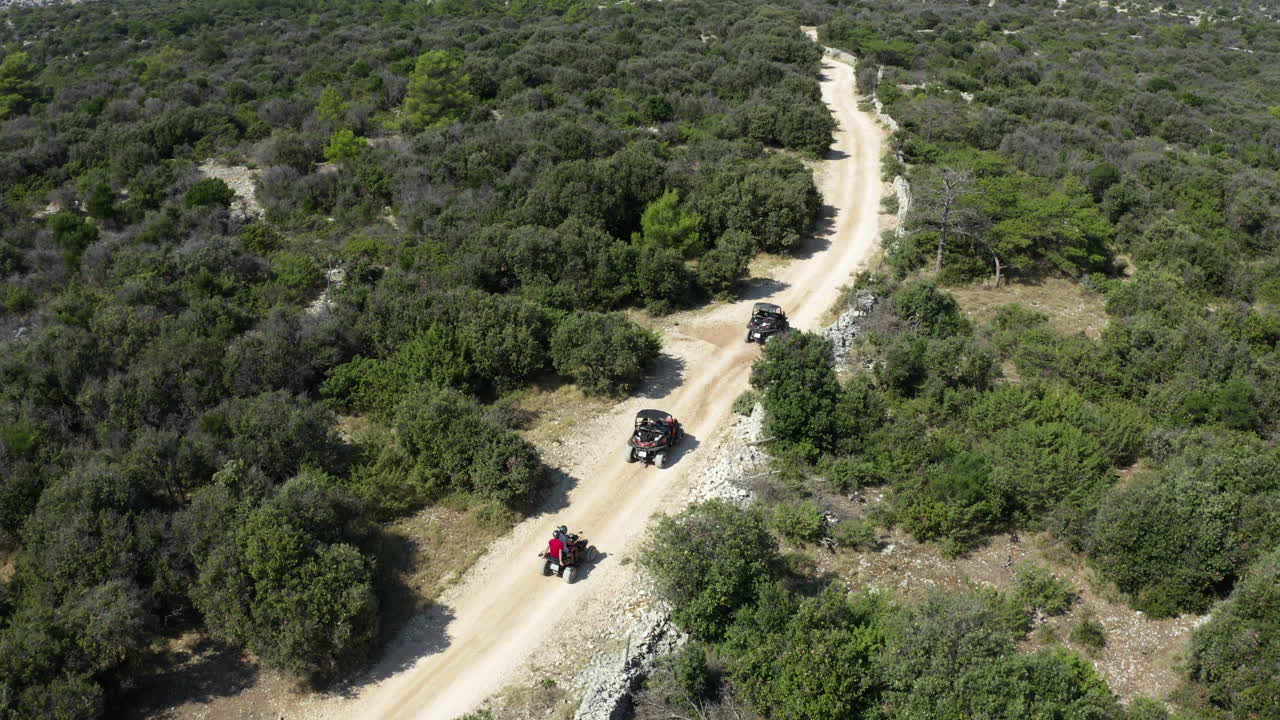 Dune buggy che partono su una lunga strada polverosa attraverso la campagna rurale. Ripresa aerea.