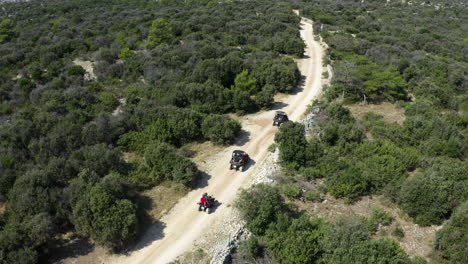 dune buggies set off on long dust road through rural countryside, aerial shot