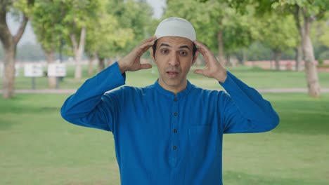 sick muslim man suffering from headache in park