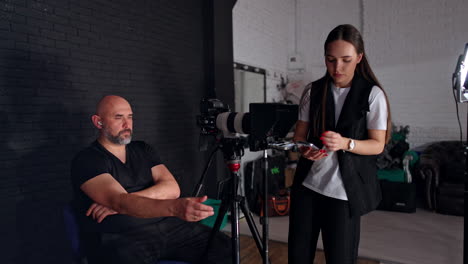 people working backstage in modern photo studio. cameraman and brunette girl taking a video.