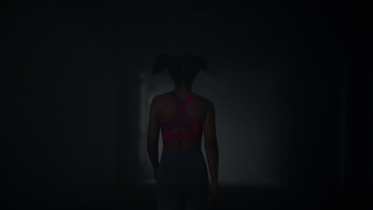 chica caminando en un pasillo oscuro. atleta tomando un descanso después de un entrenamiento de cardio