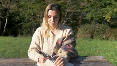 Woman-outdoors-with-notebook-and-pen-looking-to-camera