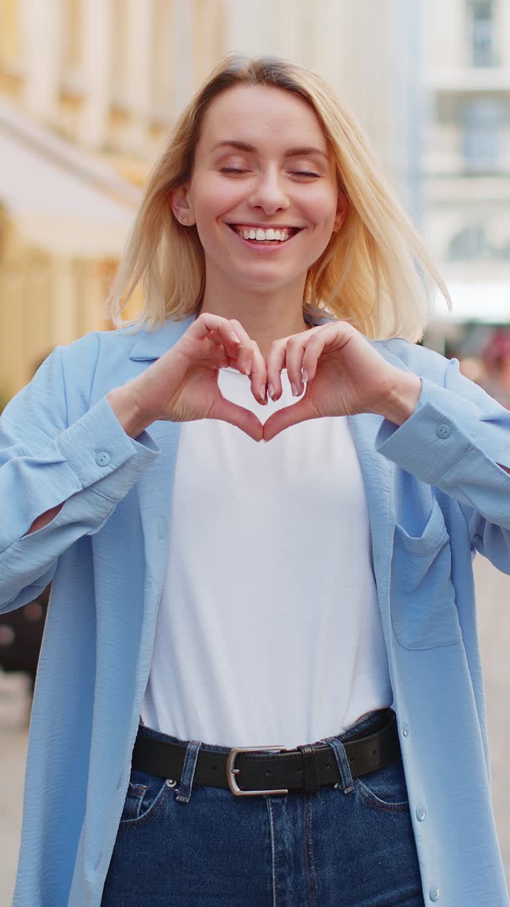 Woman makes symbol of love showing heart sign to camera charity gratitude donation positive feelings