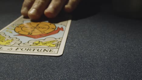 close up shot of person giving tarot card reading laying down the wheel of fortune card on table