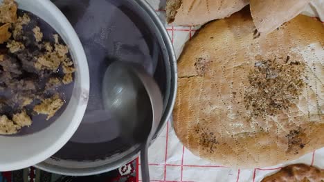 serve-purple-grey-color-vegetarian-liquid-food-in-clay-bowl-traditional-qurut-kashk-local-food-in-Khorasan-rural-village-countryside-in-Iran-desert-climate-flat-bread-tasty-delicious-Persian-cuisine