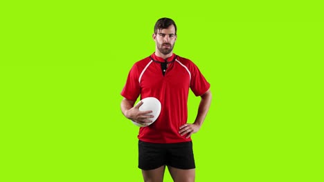 professional rugby player standing and holding a ball on green background 4k