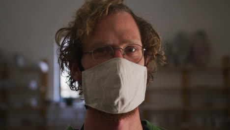 portrait of male potter wearing face mask and apron at pottery studio