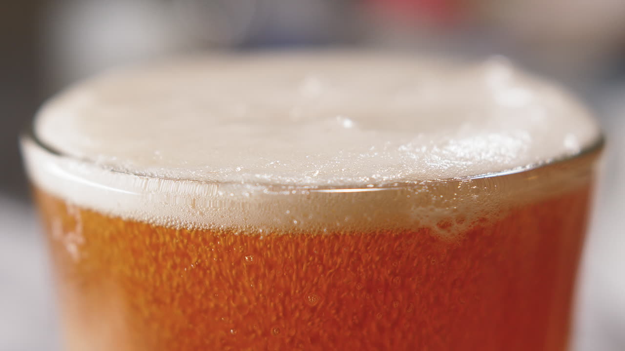 toma macro de cerveza que se vierte en un vaso de pinta y burbujas que se elevan en él 4k