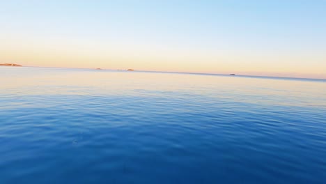 fpv aerial drone flying across a beach and over the blue water of the mediterranean sea