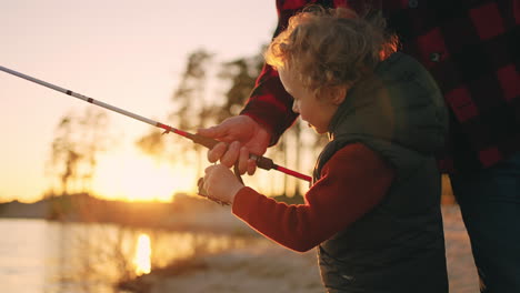 la familia está descansando en la naturaleza. el niño y el padre están pescando en el río al atardecer.
