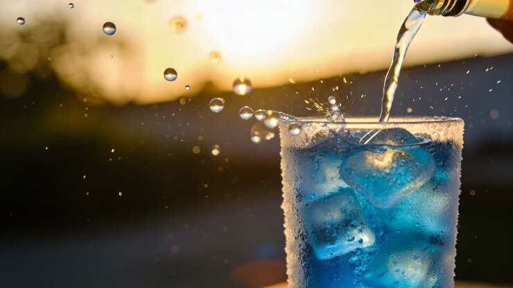 Vertical video: Hand tilting bottle and pouring blue drink into frosted glass, creating beverage ad