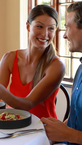 pareja sonriente usando una tableta digital en un restaurante