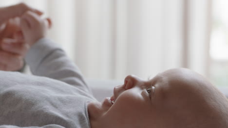 mother-holding-baby-hand-touching-fingers-nurturing-newborn-caring-for-infant-at-home-enjoying-motherhood