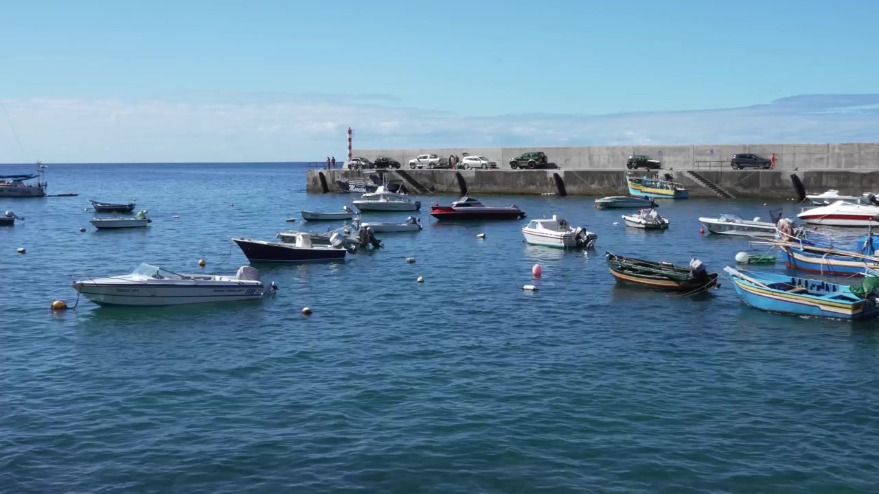 Un'ampia inquadratura cinematografica di Paul do Mar che mostra le tradizionali barche da pesca note come canoas, ormeggiate delicatamente lungo la riva. La scena cattura le calme acque dell'Atlantico