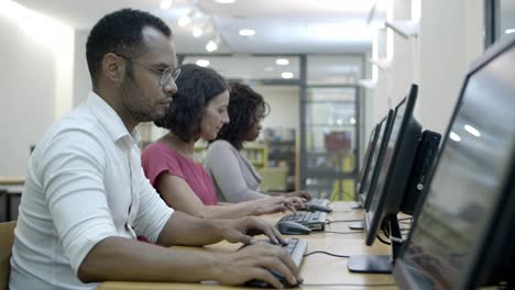 serious students passing exams by computers in class