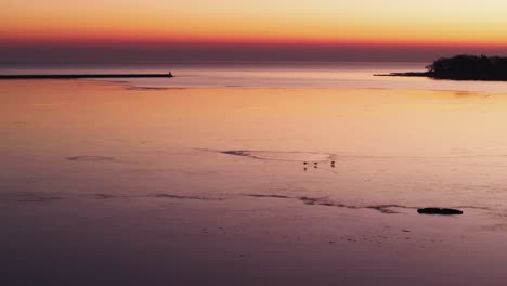 tranquila puesta de sol en port colborne con reflejos en el agua tranquila, silueta del muelle visible