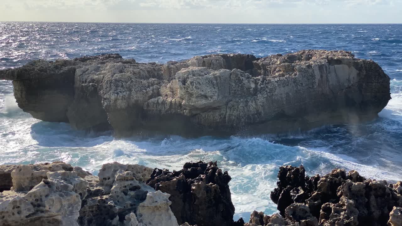 Potenti onde oceaniche che colpiscono la costa rocciosa, con un enorme spruzzo d'acqua