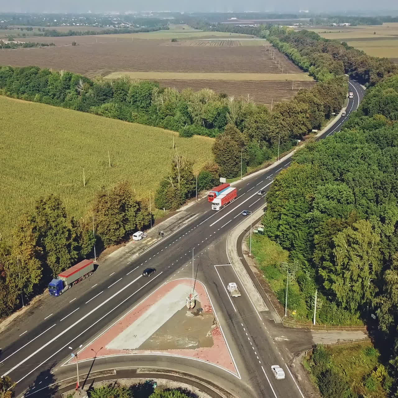 Three roads converge together in the form of triangle and cars moving on near the green nature. Road traffic is on the highway, vehicles driving on two lanes way. Top view