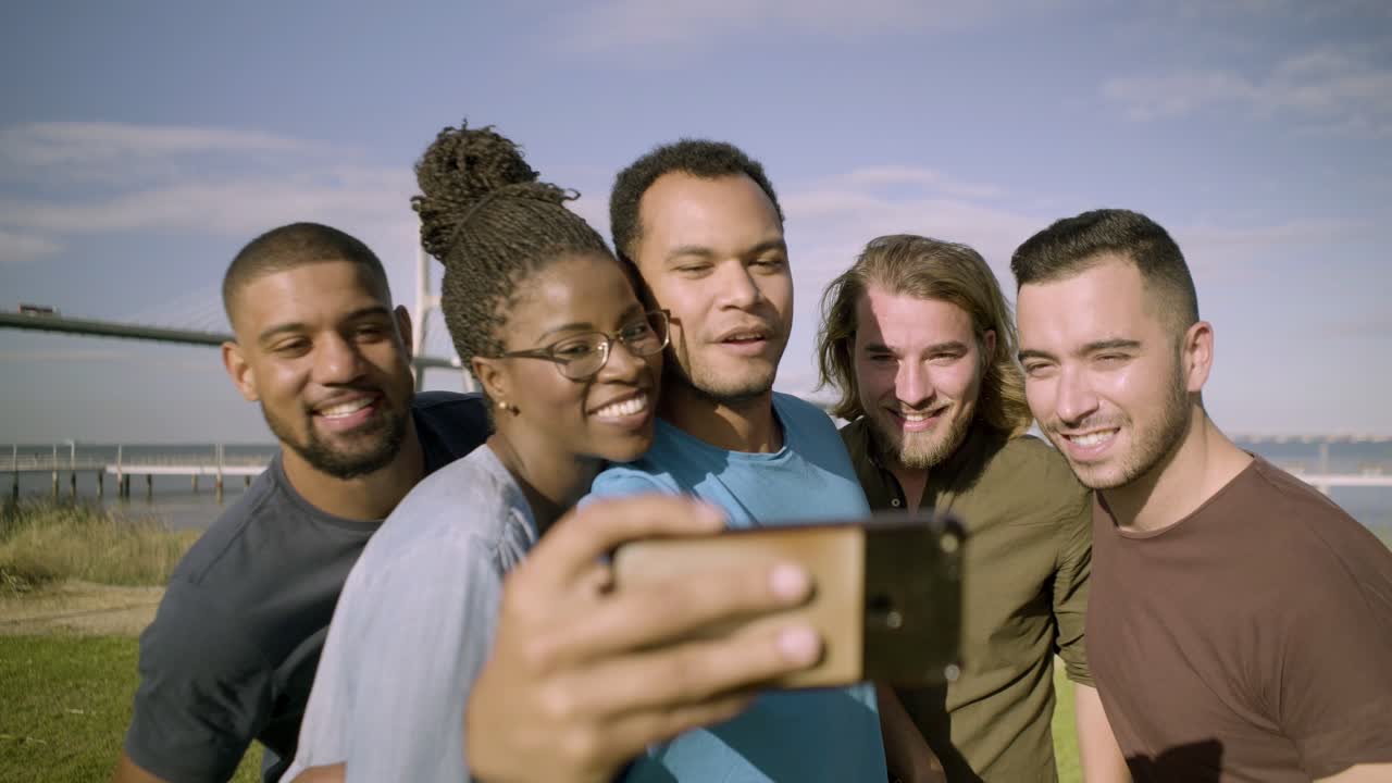 Amici felici che corrono verso lo smartphone per scattare un selfie