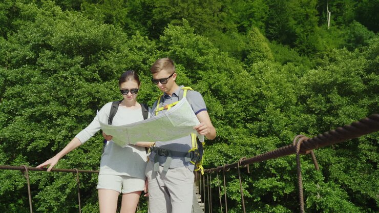 Un hombre y una mujer estudian el mapa. Están de pie en el puente con un pintoresco escenario de fondo.