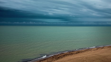una toma de lapso de tiempo del agua del mar haciendo olas en la playa y una cizalladura de viento en un cielo nublado