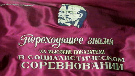 una bandera soviética envuelve un mensaje que reconoce un logro laboral