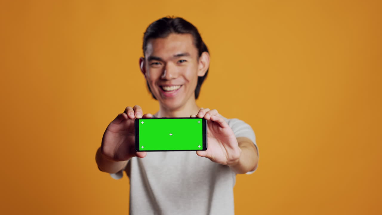 Male model holding horizontal greenscreen mobile phone