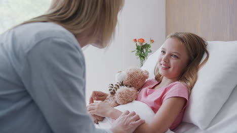 female doctor visits mother and daughter in hospital ward discussing test results on digital tablet