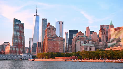 moving on boat along the green waterfront of new york, usa. beautiful high-rise skyline of metropolis at backdrop