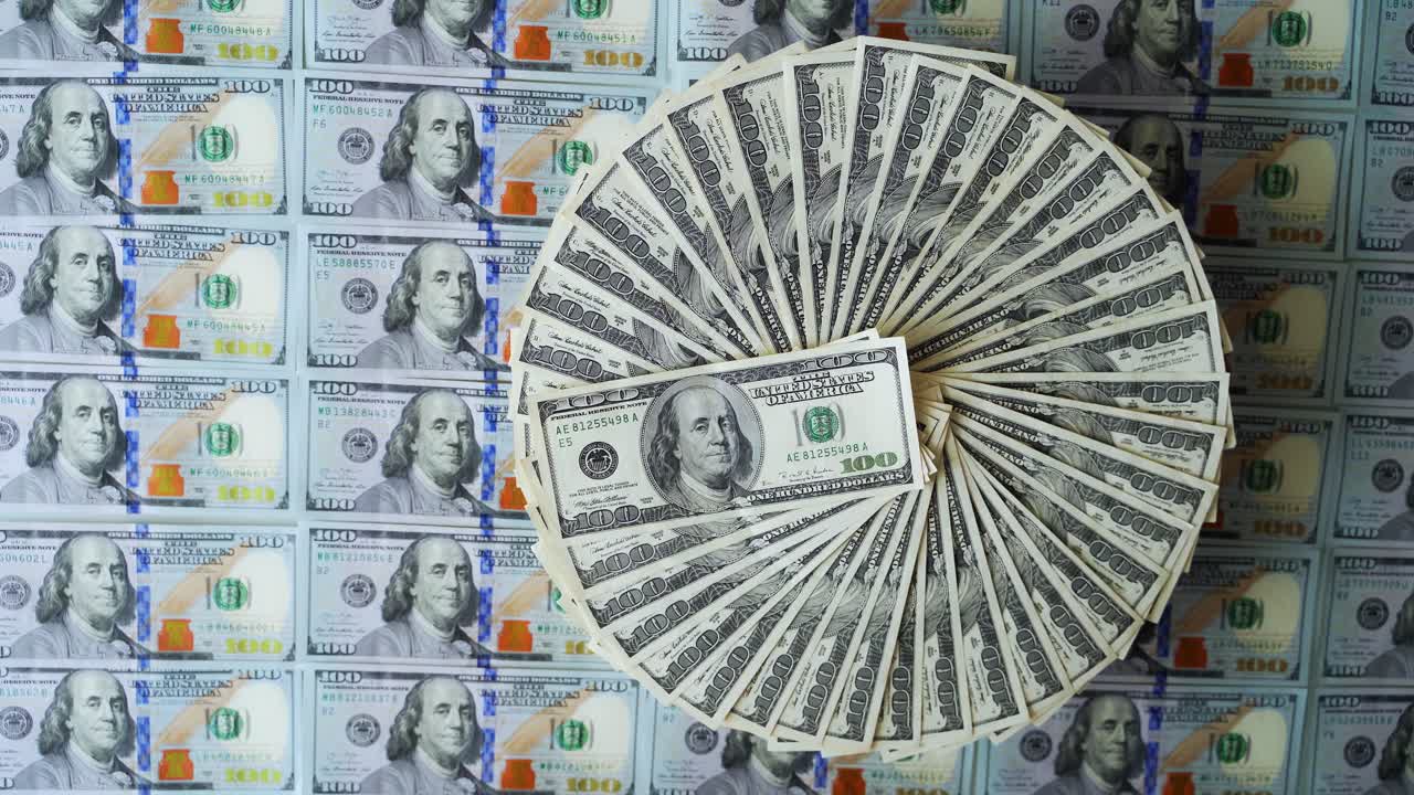 백 달러 지폐는 원형으로 되어 있으며, 백 달러의 미국 지폐의 재정적 배경은 잘 배치된 현금, 종이, 돈이 회전하고 있다.